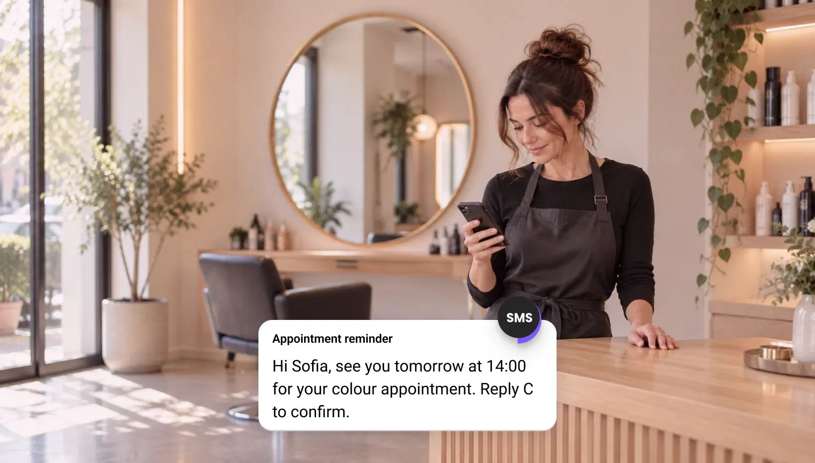 Salon owner reading an SMS appointment reminder on her phone
