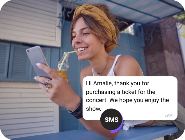 Girl drinking juice in the street checking an SMS confirmation for a concert ticket